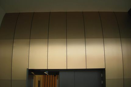 Gewölbte Wandverkleidung aus großformatigen Platten über dem Saalzugang – Bürgerhaus Lechner Bräu