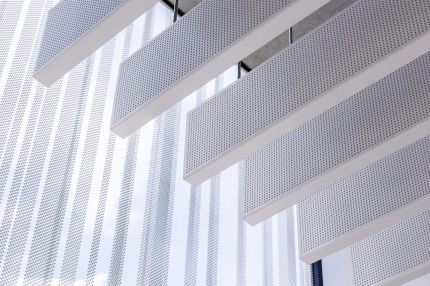 Detail der gelochten weißen Deckenlamellen vor der Glasfassade – Gymnasium Oberursel