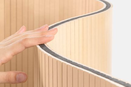 Eine Hand berührt den flexiblen Staudigel-Paravent mit schallabsorbierenden Eigenschaften.
