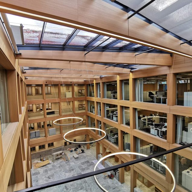 Fertiges Atrium mit Glasdach, holzfurniertem Fassadenraster und Ringleuchten – IHK Nürnberg