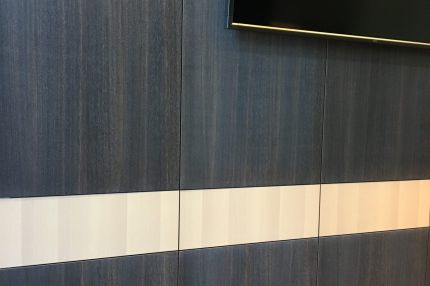 Dunkle Holz-Wandverkleidung mit hellem Band und Wandbildschirm – Justizzentrum Bochum