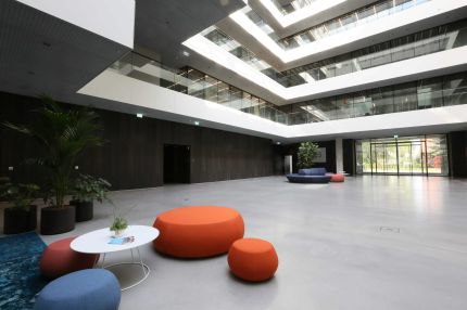 Foyer mit orangefarbenen Sitzpoufs, Galerien und dunkler Holzwand – AEB-Zentrale, Stuttgart