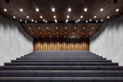 Auditorium mit Holzdecke, Downlights und Rückwand aus Nussbaum-Furnier – James-Simon-Galerie, Berlin
