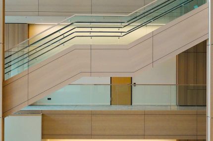 Holzverkleidete Treppe mit Glasgeländer im Lichthof – Justizzentrum Bochum