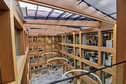 Fertiges Atrium mit Glasdach, holzfurniertem Fassadenraster und Ringleuchten – IHK Nürnberg
