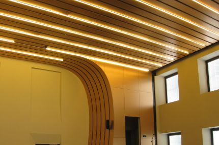 Saal mit geschwungener Holzlamellendecke und integrierten Lichtbändern – Bürgerhaus Lechner Bräu