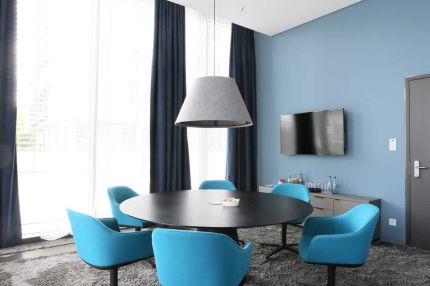 Besprechungsraum mit Rundtisch, blauen Sesseln und Filz-Pendelleuchte – AEB-Zentrale, Stuttgart