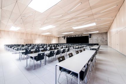 Saal mit Tischreihen unter facettierter Holzdecke mit Oberlichtern – Gymnasium Oberursel