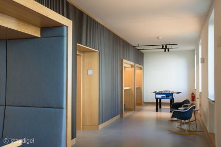 Pausenbereich mit Tischkicker, Schaukelstühlen und Lamellenwand mit Eichennischen – MOZ-Areal VR-Bank, Würzburg