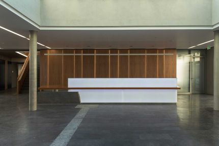 Empfangstheke im Foyer vor Holzfurnier-Wandverkleidung mit Lichtfugen – Deutsche Rentenversicherung, Würzburg