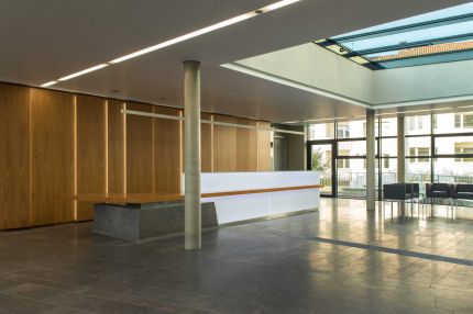 Foyer mit Empfangstheke, Holz-Wandverkleidung, Lochplattendecke und Oberlicht – Deutsche Rentenversicherung, Würzburg