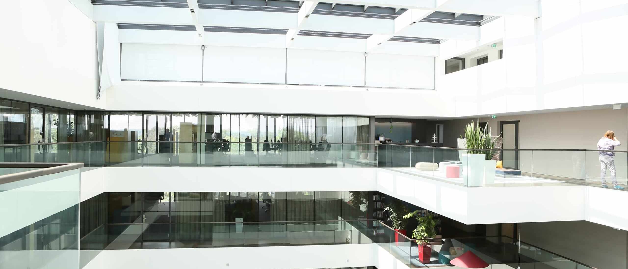 Lichthof mit Glasdach, weißen Galerien und Glasbrüstungen – AEB-Zentrale, Stuttgart
