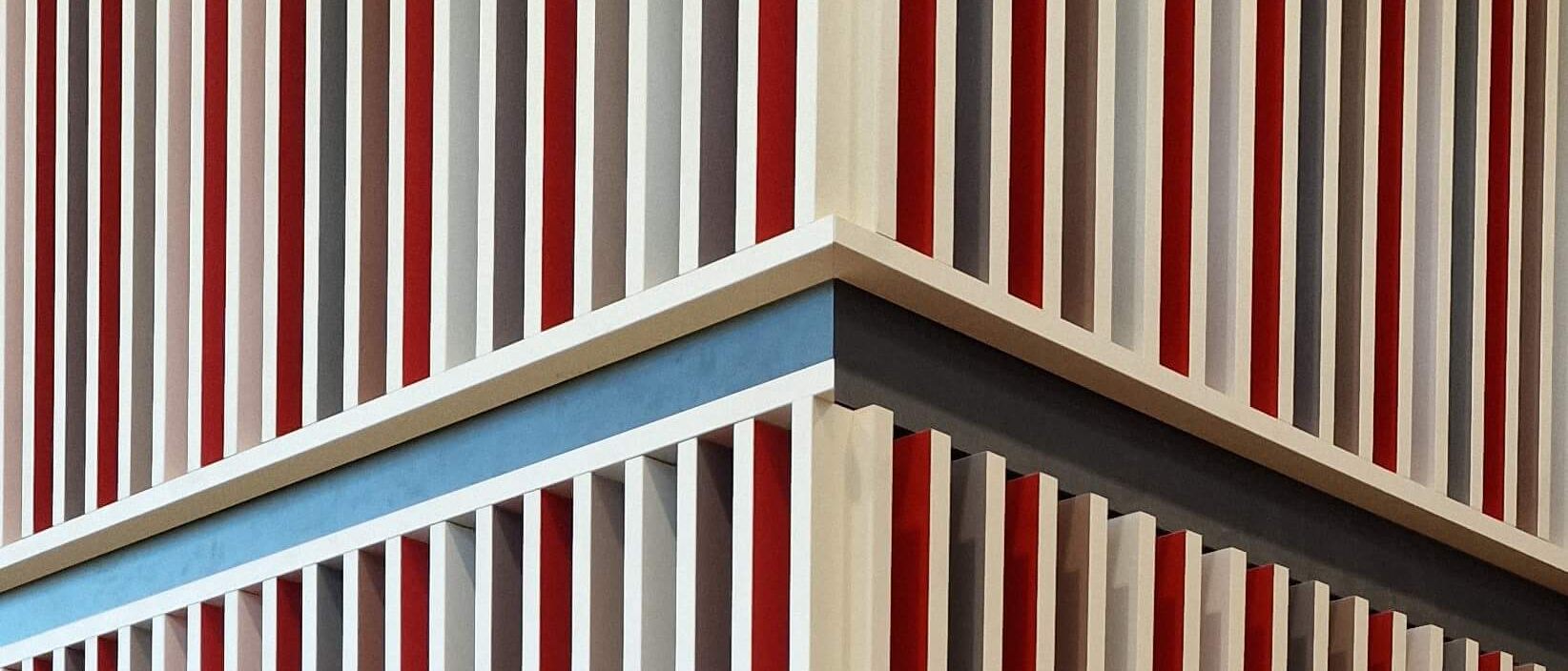Detail der Lamellenverkleidung an einer Stützenecke mit roten und grauen Feldern – Mensa Würzburg