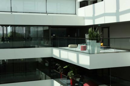 Galerie mit Loungebereich, Pflanzen und Glasbrüstung im Lichthof – AEB-Zentrale, Stuttgart