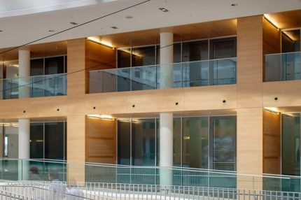 Holzverkleidete Galeriefassade mit weißen Säulen über geschwungener Treppe – Europäisches Patentamt