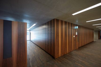 Garderobe mit Schließfächern und Wandverkleidung in Nussbaum-Furnier unter Sichtbetondecke – James-Simon-Galerie, Berlin