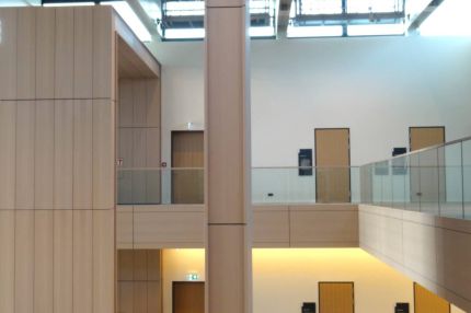 Lichthof über mehrere Geschosse mit holzverkleideten Wänden und Glasbrüstungen – Justizzentrum Bochum