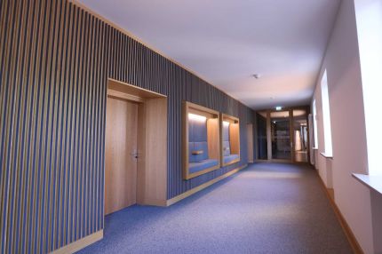 Flur mit Lamellenwand, Eichentür und zwei Sitznischen, rechts Fensterseite – MOZ-Areal VR-Bank, Würzburg