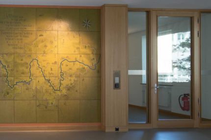 Flur mit Eichen-Wandverkleidung, Landkarten-Wandbild mit Flusslauf und Glastür – MOZ-Areal VR-Bank, Würzburg
