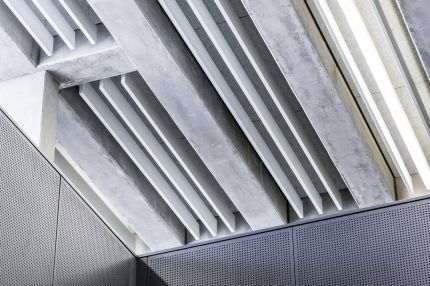 Detail der Betonrippendecke mit Lichtbändern über anthrazitfarbenen Lochplatten – Gymnasium Oberursel