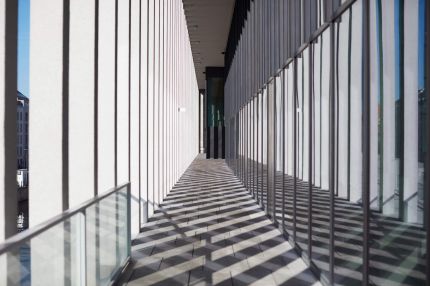 Kolonnadengang mit Schattenmuster der Stützen auf dem Steinboden – James-Simon-Galerie, Berlin
