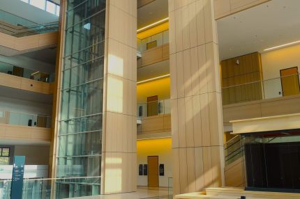 Lichthof mit holzverkleideten Pfeilern und gläsernem Aufzugsschacht – Justizzentrum Bochum