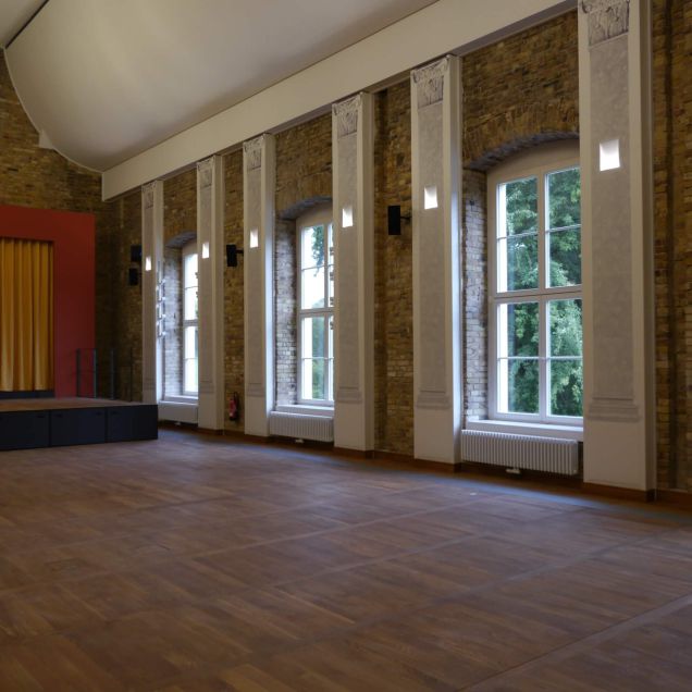 Festsaal mit Bühne, Rundbogenfenstern und Sichtmauerwerk – Neues Schloss Bad Muskau