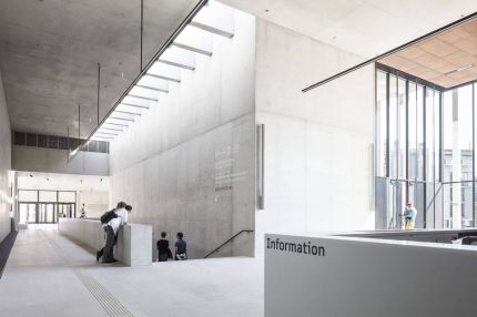 Foyer mit Sichtbetonwänden, Oberlichtband, Treppenabgang und Informationstheke – James-Simon-Galerie, Berlin