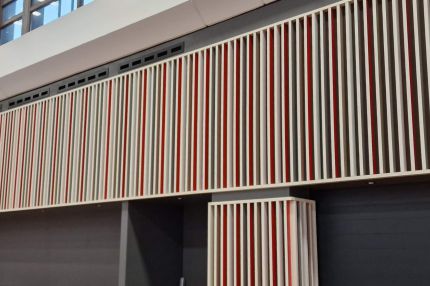 Lamellenfries über dunklen Toren, darüber Fensterband der Halle – Mensa Würzburg
