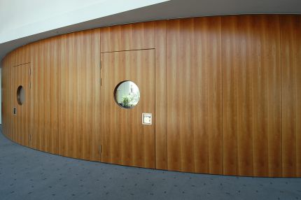 Gebogene Holz-Wandverkleidung mit Türen und Bullaugenfenstern, Außenseite – IHK Potsdam