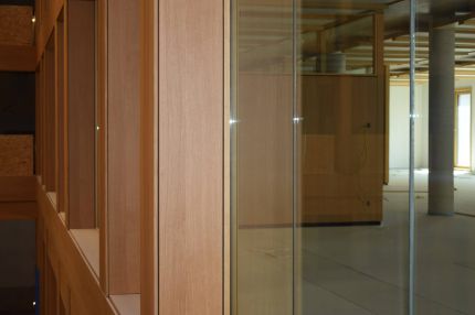 Nahaufnahme der furnierten Pfeilerverkleidung neben Glaswand mit Blick ins Bürogeschoss – IHK Nürnberg