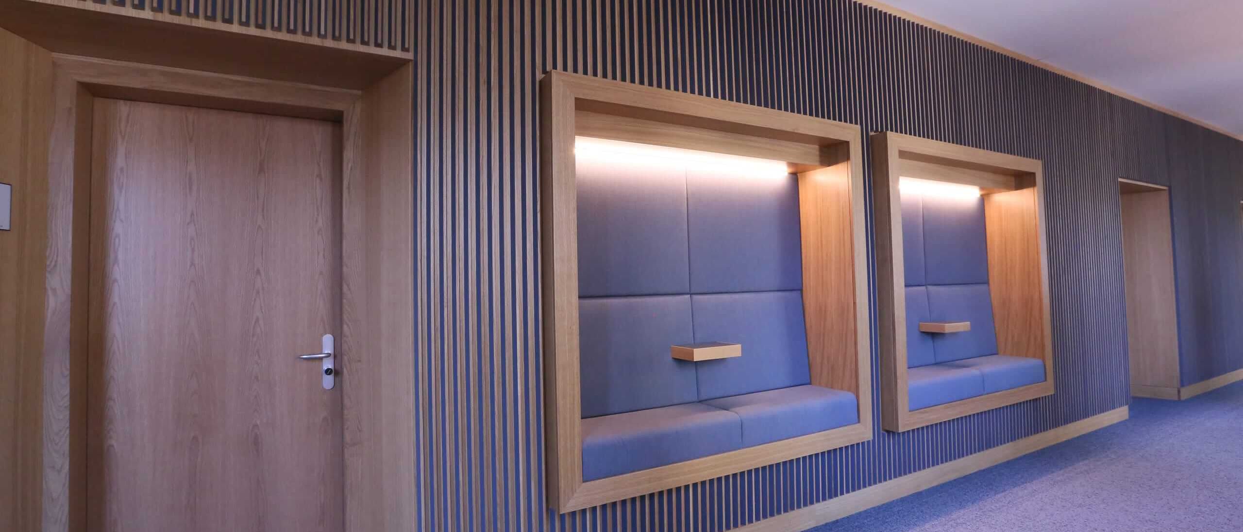 Zwei gepolsterte Sitznischen mit Lichtband in der Lamellenwand neben Eichentür – MOZ-Areal VR-Bank, Würzburg