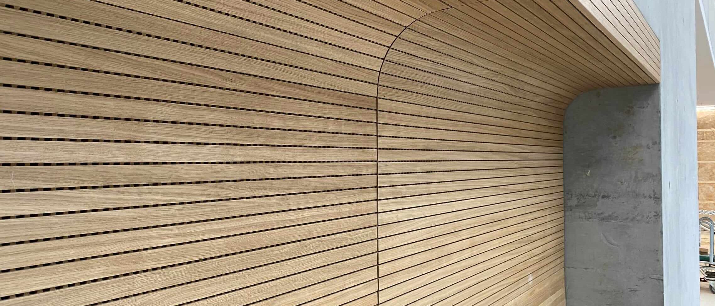 Gerundete Wand-Decken-Verkleidung aus Eichen-Schlitzplatten an Betonwand – Technisches Rathaus Mannheim