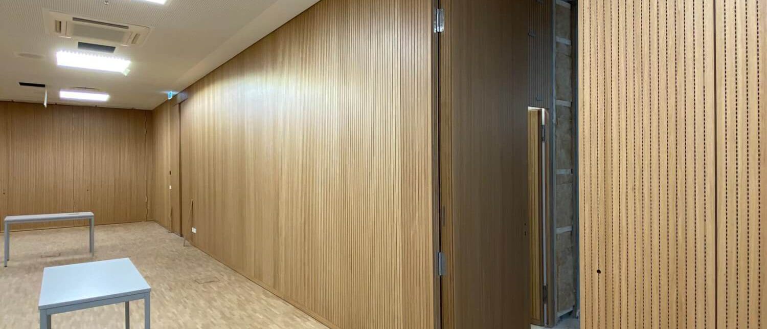Langer Raum mit Eichen-Schlitzplatten und geöffneter verdeckter Tür – Technisches Rathaus Mannheim