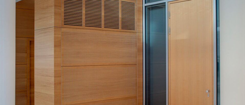 Holzverkleideter Einbau mit Lüftungsgitter neben Glastür unter Lochdecke – Europäisches Patentamt