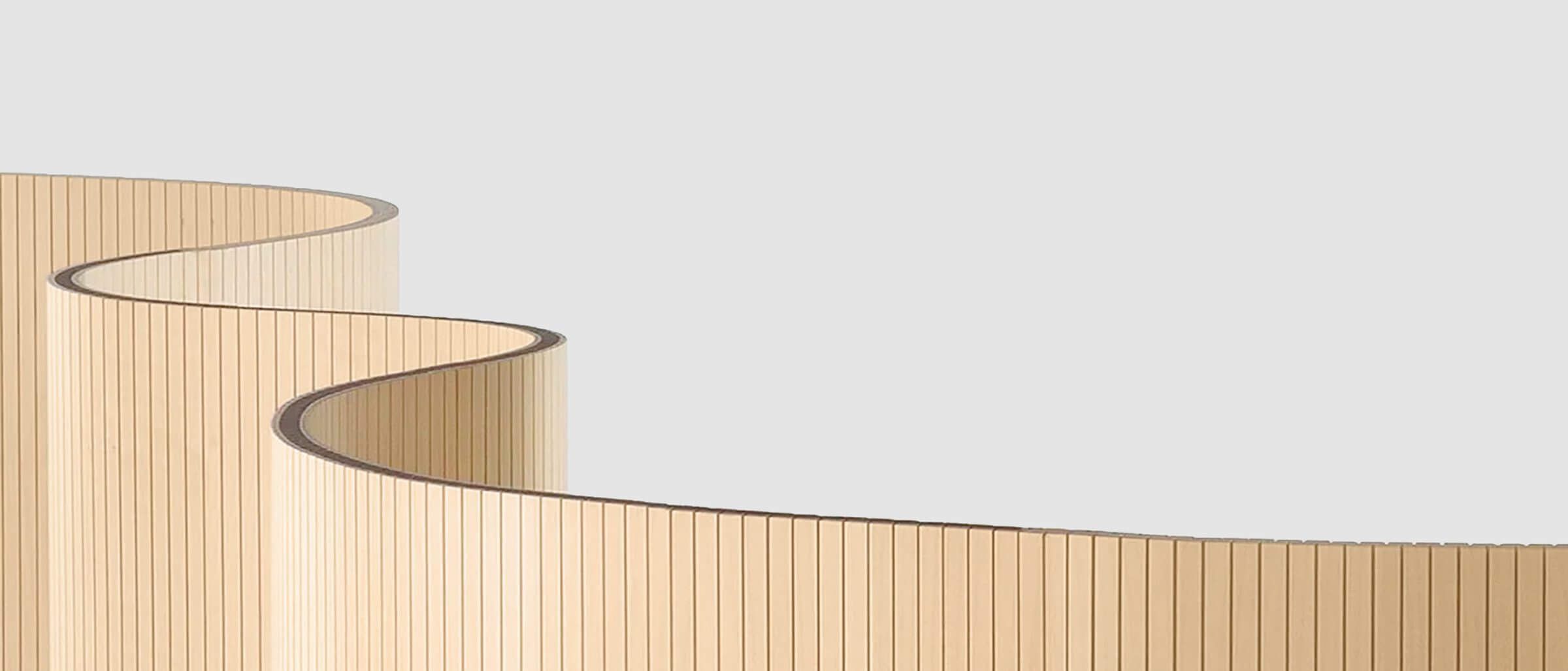 Ein geschwungener Raumteiler aus Holz von Staudigel schafft elegante Abgrenzungen.