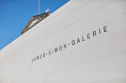 Detail des Schriftzugs auf der Natursteinwand vor blauem Himmel – James-Simon-Galerie, Berlin