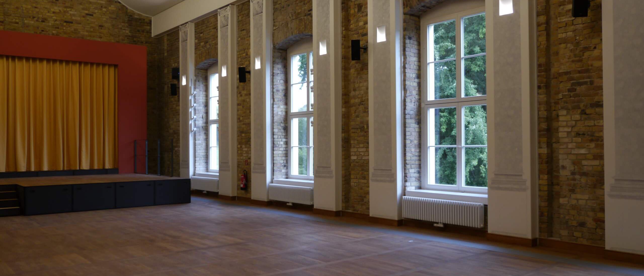 Festsaal mit Bühne, Rundbogenfenstern und Sichtmauerwerk – Neues Schloss Bad Muskau