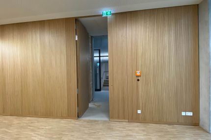 Eichen-Schlitzplatten-Wand mit Durchgang zum Treppenhaus unter Lochdecke – Technisches Rathaus Mannheim