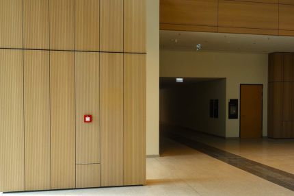 Foyer mit holzfurnierter Wandverkleidung und Galerie mit Glasbrüstung – Justizzentrum Bochum