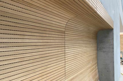 Gerundete Wand-Decken-Verkleidung aus Eichen-Schlitzplatten an Betonwand – Technisches Rathaus Mannheim
