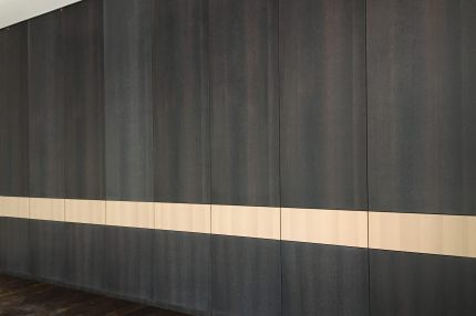 Dunkle furnierte Akustik-Wandverkleidung mit hellem Querband – Justizzentrum Bochum