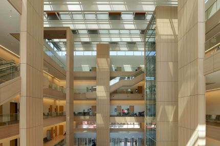 Lichthof unter Glasdach mit holzverkleideten Pfeilern und Galerien – Justizzentrum Bochum