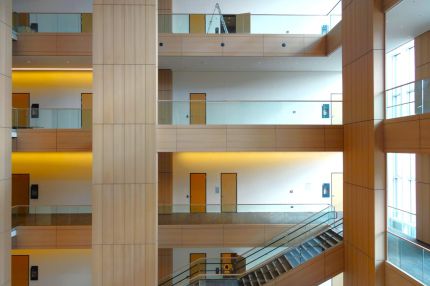Galerien mit holzverkleideten Brüstungen und Pfeilern über mehrere Geschosse – Justizzentrum Bochum