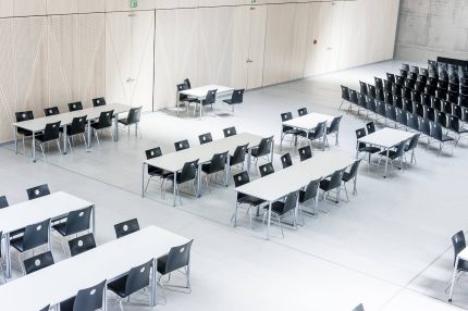 Mensa mit Tischreihen vor heller Holz-Wandverkleidung mit Rautenfugen – Gymnasium Oberursel