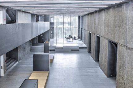 Foyer mit Lichtlamellendecke, Vitrinen und Galerie vor Betonwand – Gymnasium Oberursel