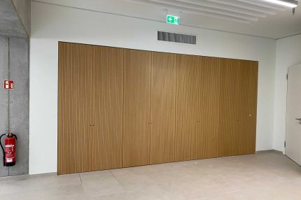 Flur mit Wandverkleidung aus Eichen-Schlitzplatten mit flächenbündigen Türen und Lamellendecke – Technisches Rathaus Mannheim