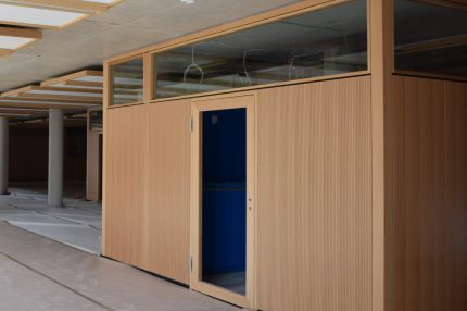 Raum-in-Raum-Modul mit Schlitzplatten in Holzfurnier und Oberlichtband im Bürogeschoss – IHK Nürnberg