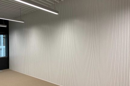 Lange Wand mit weißen Schlitzplatten, Fenster und Teppichboden – Technisches Rathaus Mannheim