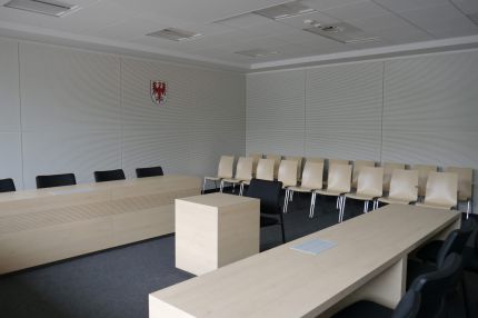 Sitzungssaal mit weißer Schlitzplatten-Wandverkleidung und Landeswappen – Sparkasse Spree-Neiße, Cottbus
